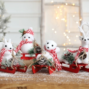 Christmas snowman and reindeer figurines on red sleds with pine cones tabletop decor