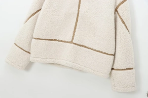 Close-up of off-white fleece jacket detailing plush texture and brown stitching accents