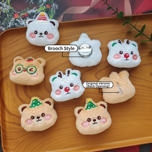 Cute Christmas bear and bunny plush brooches with festive holiday decorations on wood