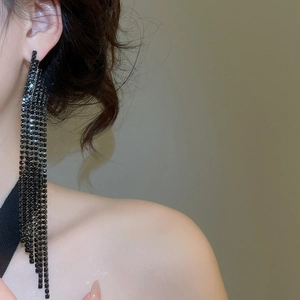 Detail shot of long black rhinestone fringe earrings on a model with elegant tassel drops