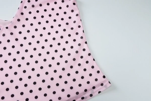 Macro detail of pink mesh fabric with black polka dots and fine textile texture