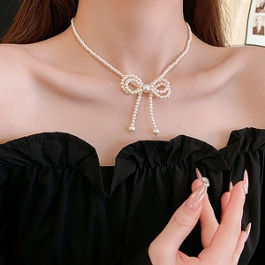 Detail of white crystal pearl necklace with bow design worn on a model's neck