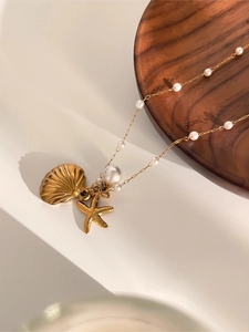 Detailed view of sea shell, starfish, and pearl charms on a stylish gold necklace