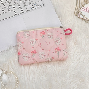 Flat lay of quilted pink rabbit pouch with floral prints on a white plush background