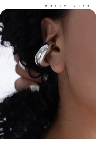 Macro shot of minimalist silver ear cuff showing smooth polished mirror surface texture