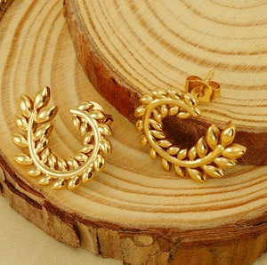 Macro shot of gold-plated wheat ear studs with elegant leaf texture on a wooden stand