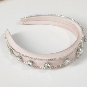 Macro detail of pink satin headband with rows of sparkling rhinestones and pearl accents