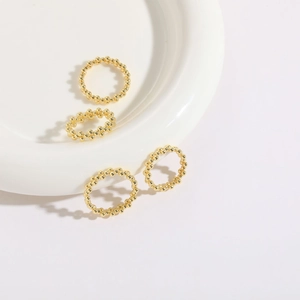 Detailed top view of four 14K gold plated beaded rings on a white ceramic plate