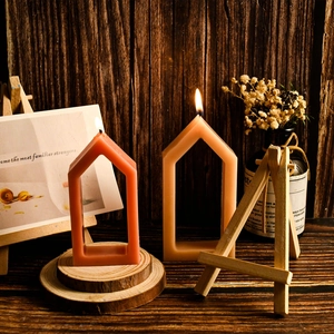 Close-up of lit hollow house-shaped candles on a rustic wooden stand for home decor