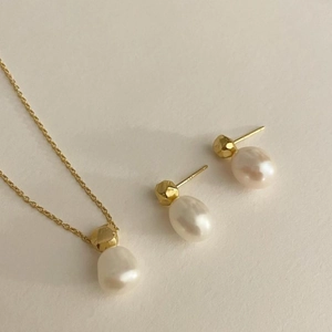 Detail view of gold metal and oval pearl jewelry set including necklace and earrings
