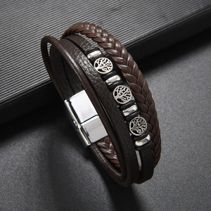 Détail des breloques arbre de vie sur un bracelet multicouche en cuir marron tressé avec fermoir