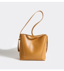 Macro view of a minimalist yellow leather bucket bag with reinforced bottom stitching