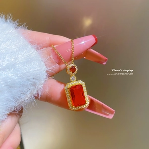Close-up of gold titanium necklace with red square pendant and micro-inlaid zircon stones