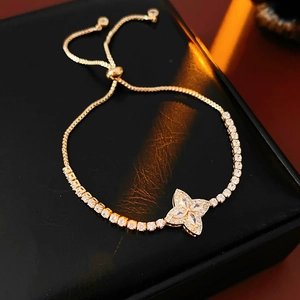 Macro detail of golden flower bracelet with white zircons on premium black leather