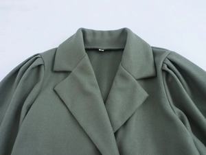 Detail of green wool coat showing structured lapel collar and stylish puff sleeve texture