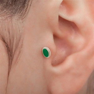 Macro shot of a tiny oval green gemstone ear stud with silver braided edge on tragus