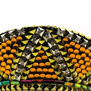 Macro detail of gold pyramid studs and orange crystals on a sparkling party captain hat