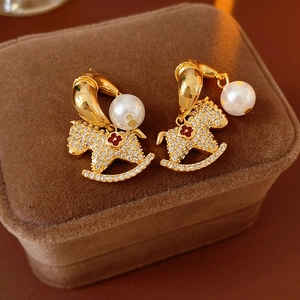 Detail of rocking horse earrings with red flowers and white pearls on velvet box