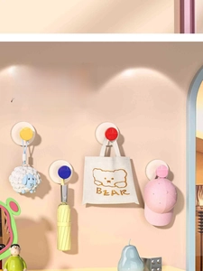 Detailed view of colorful suction wall hooks holding a bag, umbrella, and a hat