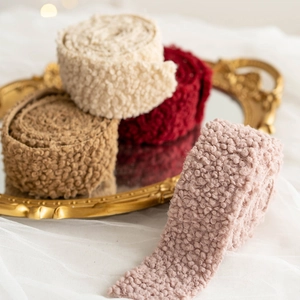 Christmas wool felt ribbons in beige, brown, red and pink displayed on a decorative mirror