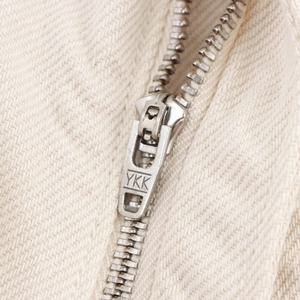 Dettaglio della cerniera metallica YKK su pantaloncini di cotone beige a vita alta