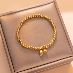 Golden beaded bracelet with lotus seed and bud pendants on a premium jewelry box