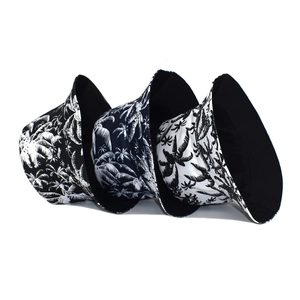 Detail of three colors of coconut tree print bucket hats in black, blue and white canvas