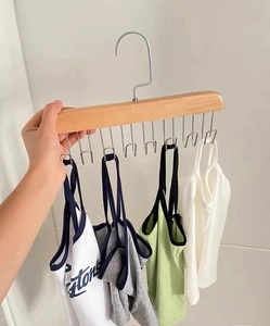 Close-up of a multi-hook solid wood hanger organizing several colorful camisole tops