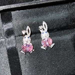 Close-up of rabbit earrings with pink gemstones and sparkling pavé crystals in a gift box