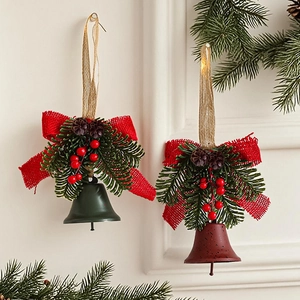 Christmas bell ornaments with red burlap bows, pine needles and cones on white wall