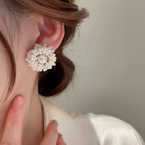 Detail view of model wearing elegant pearl flower cluster earrings with gold plating