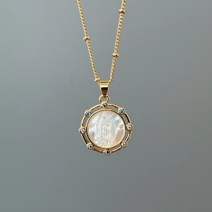 Golden necklace with Guadalupe virgin shell pendant and colorful crystals on neutral background