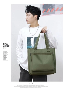 Detail of olive green nylon tote bag featuring front zipper pockets and durable shoulder straps