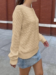 Close-up of beige cable knit sweater showing detailed texture and ribbed cuffs