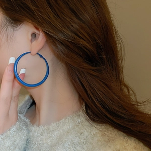 Close-up of a large vibrant Klein blue circular hoop earring worn by a female model