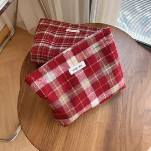 Détail rapproché des pochettes en laine à carreaux rouges et blancs sur table en bois
