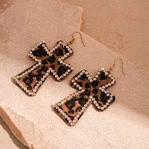 Detailed view of leopard print cross earrings with sparkling rhinestones and gold hooks