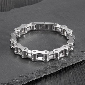 Macro shot of silver bicycle chain style stainless steel bracelet on a dark stone surface