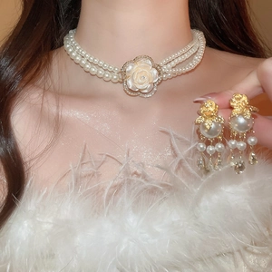 Detail of elegant multi-layer pearl necklace and drop earrings worn by a model