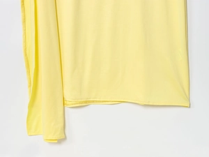 Detailed close-up of yellow backless long dress hemline stitching and fabric drape