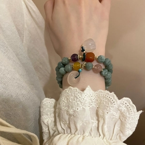 Detail of double-layer beaded bracelet with green chalcedony and colorful charms on lace sleeve