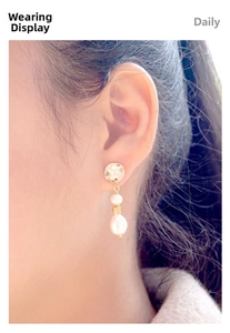 Close-up of elegant gold baroque pearl earrings with hammered metal discs on model