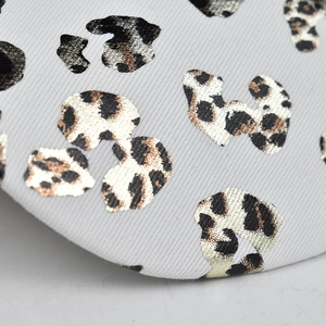 Détail du tissu à imprimé léopard avec dorures sur une casquette en coton blanc