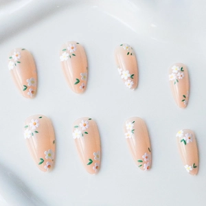 Elegant almond press-on nails featuring white daisies and green leaves on nude pink base