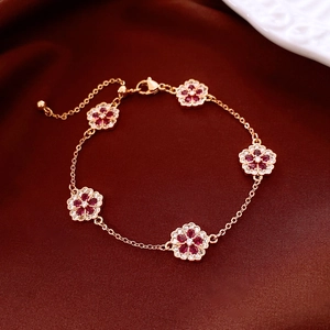 Detail of 18k rose gold flower bracelet with red ruby-colored petals on silk fabric