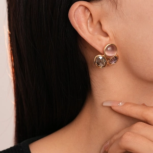 Vue détaillée de boucles d'oreilles opale rose et marron portées avec monture dorée