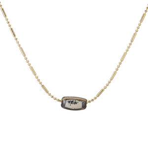Detailed macro view of a gold bamboo chain necklace with a textured ceramic bead pendant