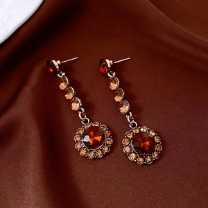 Détail de boucles d'oreilles dorées vintage avec pierres ambrées et cristaux fins