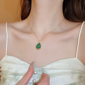 Detailed view of an elegant gold necklace featuring a green teardrop-shaped gemstone pendant