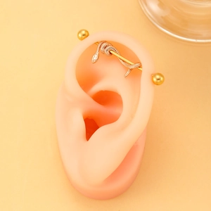 Vintage golden snake industrial barbell piercing on silicone ear model